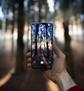 person holding black smartphone taking photo of city lights during night time